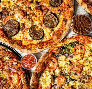 Melanzane and veggie pizzas with a cup of tomato dip