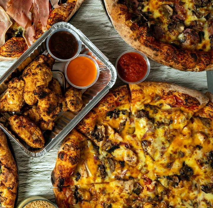 Specialty pizzas and a tray of chicken wings