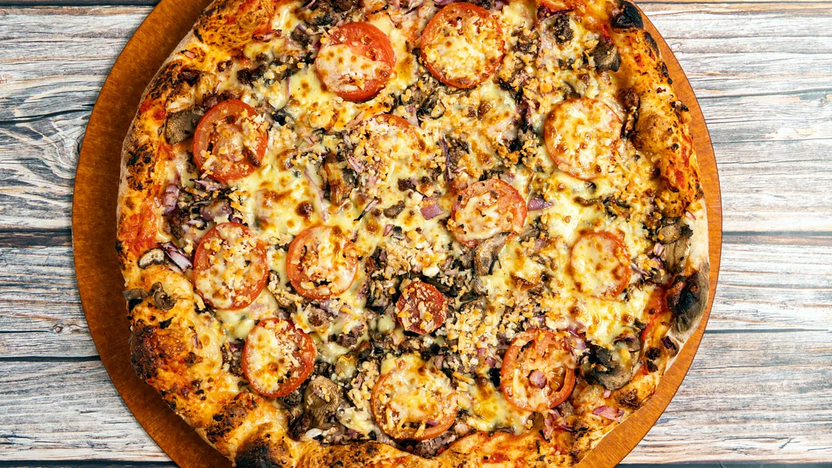 Authentic pizza with ground beef, mushrooms, red onions, tomatoes and feta